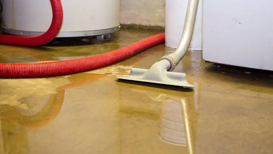Wet vacuum removing water from a floor beside a water heater